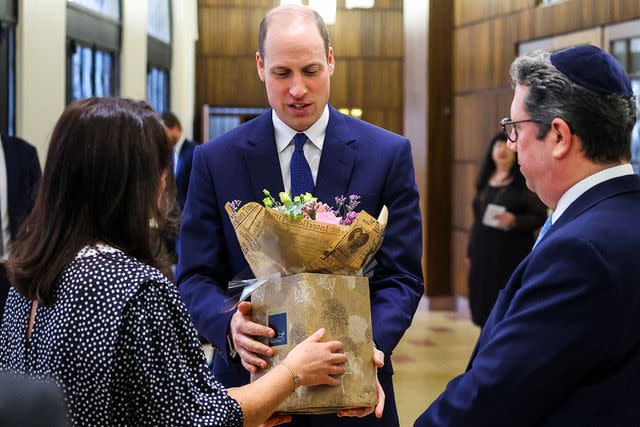 <p>TOBY MELVILLE/POOL/AFP via Getty Images</p> Prince William receives a bouquet of flowers for his wife Kate Middleton during a visit to the Western Marble Arch Synagogue, in London, on February 29.