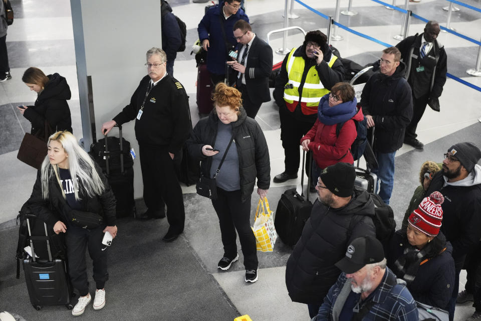 Travelers wait and look outside for an airport shuttle bus from inside of Terminal 3 as airport train doesn't run due to cold weather at the O'Hare International Airport in Chicago, Sunday, Jan. 14, 2024. Wind chill warning is in effect as dangerous cold conditions continue in the Chicago area. (AP Photo/Nam Y. Huh)