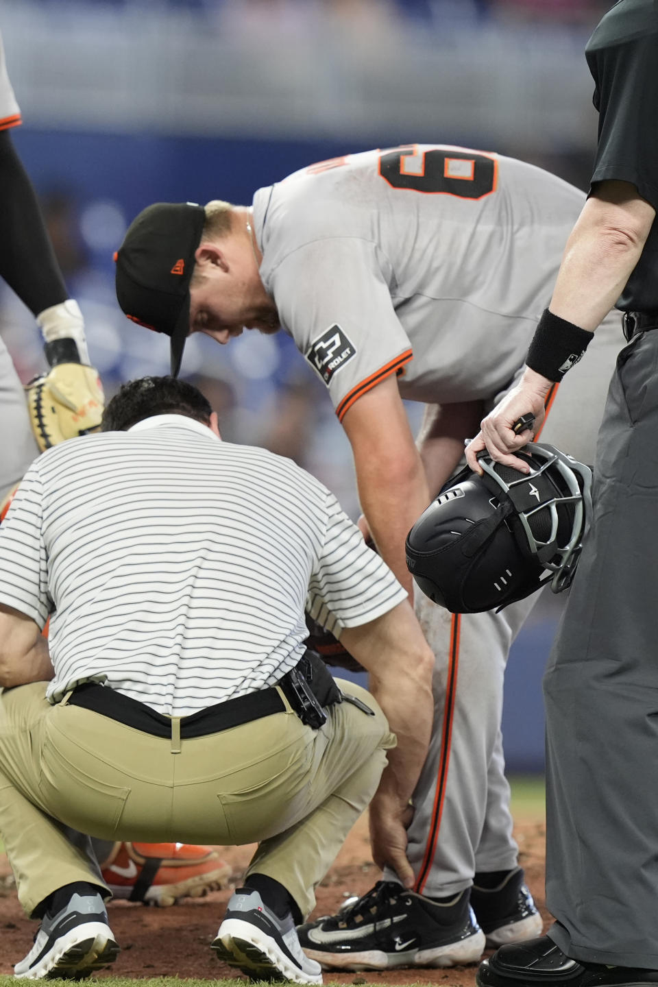 A San Francisco Giants trainer checks the leg of pitcher Keaton Winn after he was hit by ground ball during the sixth inning of a baseball game against the Miami Marlins, Wednesday, April 17, 2024, in Miami. (AP Photo/Marta Lavandier)