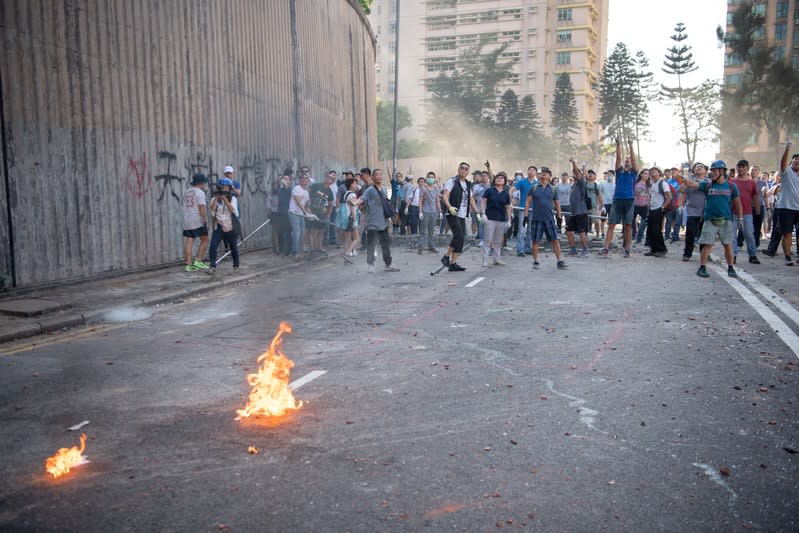 Las personas que limpian las barricadas improvisadas en las carreteras colocadas por los manifestantes señalan a los manifestantes después de que un cóctel molotov fuera arrojado fuera de la Universidad de Hong Kong en Hong Kong, China, el 16 de noviembre de 2019