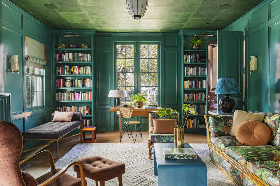 In a rich, saturated study decked in shades of green, the ceiling is covered in sheets of hand-painted paper