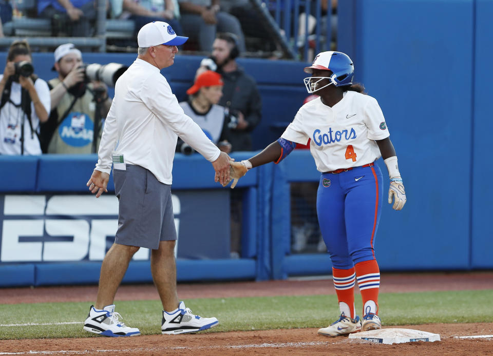 Florida coach Billy Napier and Charla Echols (4) celebrate after Echols reaches third base against Oregon State during the fifth inning of an NCAA softball Women's College World Series game Thursday, June 2, 2022, in Oklahoma City. (AP Photo/Alonzo Adams)