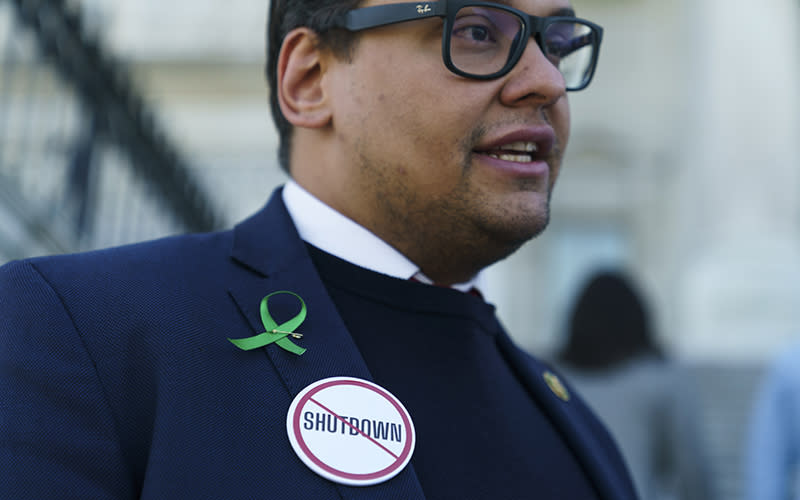 A closeup is shown of Rep. George Santos' (R-N.Y.) jacket where he wears large round button that says "shutdown" with a large red circle and line across it to demonstrate against a shutdown.