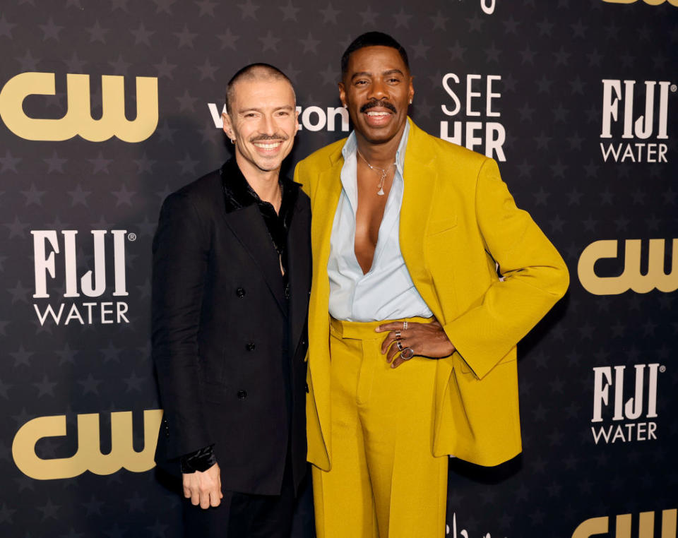 Colman and Raúl on a red carpet posing for the camera; one in a blazer, the other in a suit