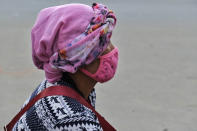 A Naga woman wears a face mask and sits by the side of a road selling poultry in Kohima, capital of the northeastern Indian state of Nagaland, Saturday, Aug. 8, 2020. As India hit another grim milestone in the coronavirus pandemic on Friday, crossing 2 million confirmed cases and more than 41,000 deaths, community health volunteers went on strike complaining they were ill-equipped to respond to the wave of infection in rural areas. (AP Photo/Yirmiyan Arthur)