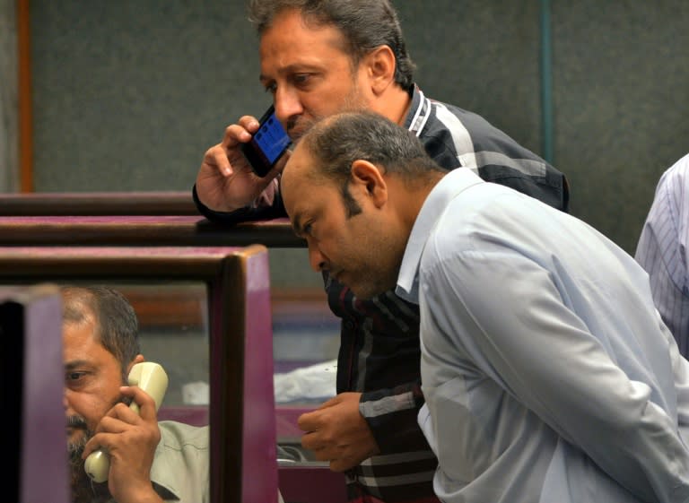 Pakistani stockbrokers talk on their phones as they watch share prices during a trading session at the Karachi Stock Exchange (KSE) in Karachi on September 2, 2015