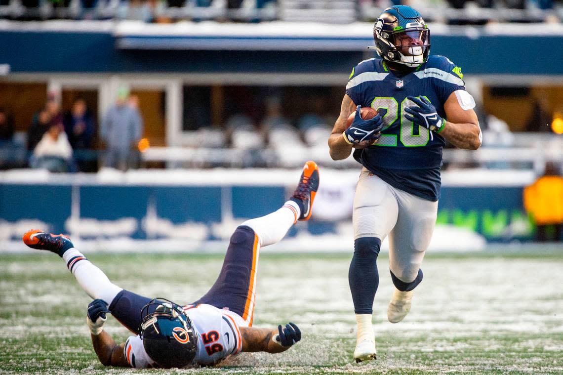 Seattle Seahawks running back Rashaad Penny (20) runs down the sideline after stiff-arming Chicago Bears linebacker Bruce Irvin (55) during the fourth quarter of an NFL game on Sunday afternoon at Lumen Field in Seattle.
