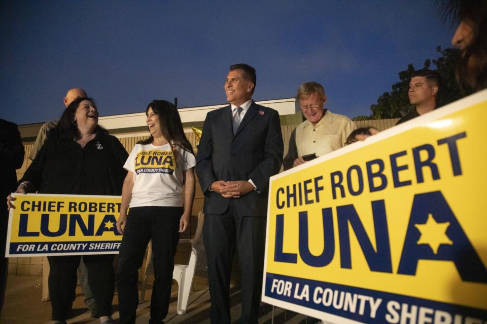 A man stands with others, some carrying signs that say "Chief Robert Luna for LA County Sheriff"
