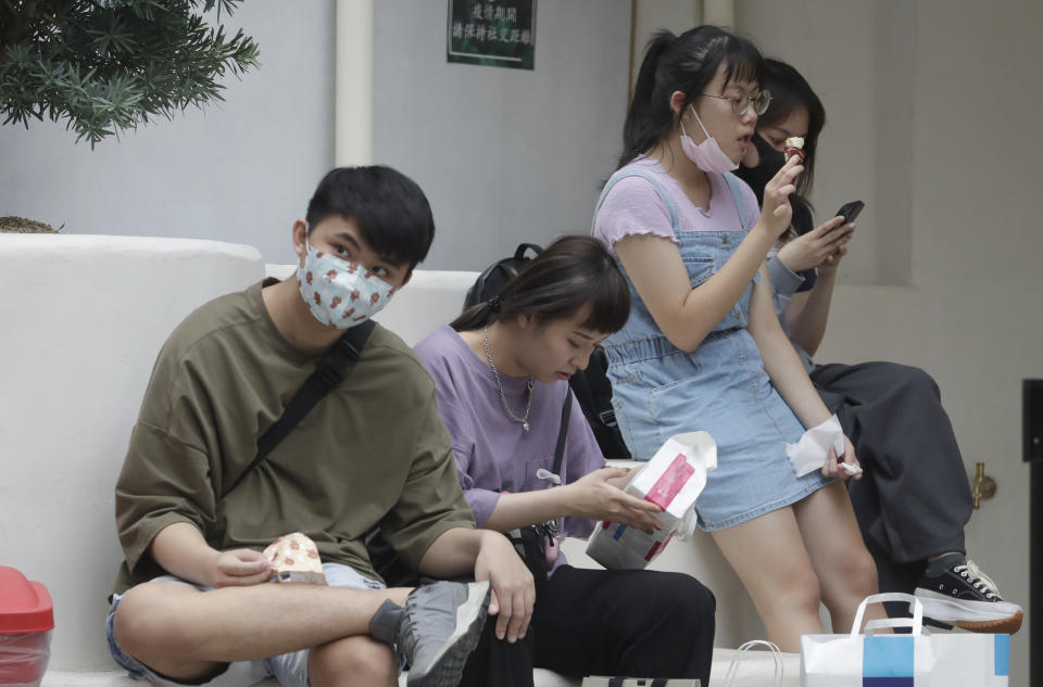 People take off their masks to eat ice cream in Taipei, Taiwan, Thursday, April 28, 2022. Taiwan, which had been living mostly free of COVID-19, is now facing its worst outbreak since the beginning of the pandemic with over 11,000 new cases reported Thursday. (AP Photo/Chiang Ying-ying)