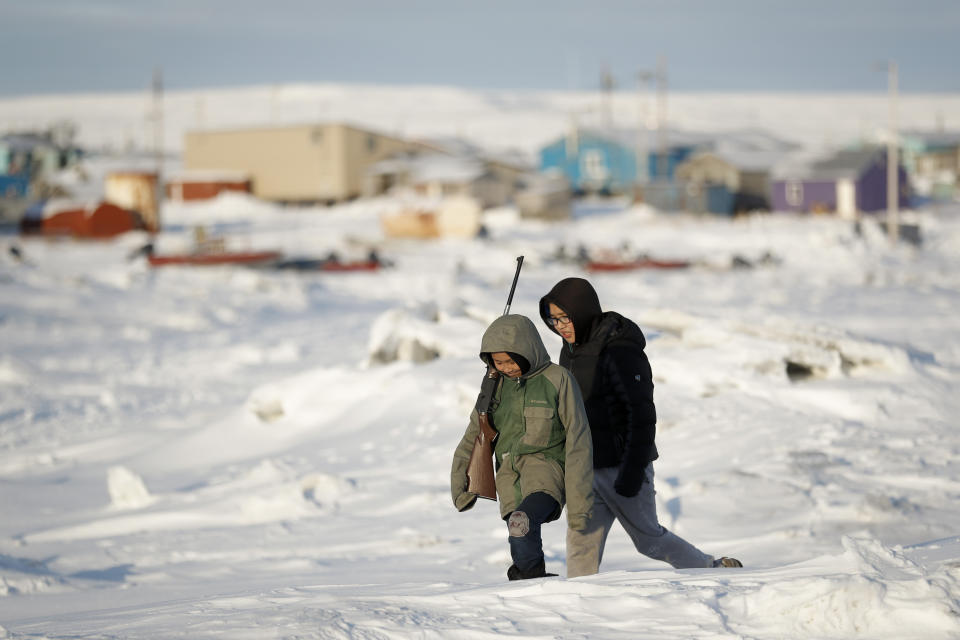 FILE - In this Jan. 18, 2020, file photo, George Chakuchin, left, and Mick Chakuchin walk on ice over the Bering Sea in Toksook Bay, Alaska, a mostly Yuip'ik village. Native American leaders are raising questions about how $8 billion in federal coronavirus relief tagged for tribes will be distributed, with some arguing that for-profit Alaska Native corporations shouldn't get a share of the funding. (AP Photo/Gregory Bull, File)