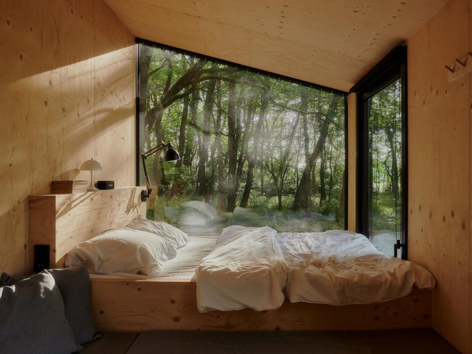 A look inside a Raus cabin with a bed near windows.