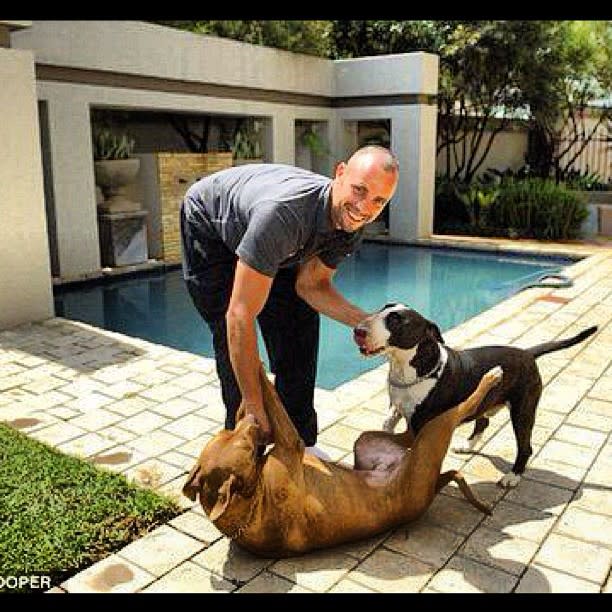 Oscar Pistorius playing with his two dogs by the pool.