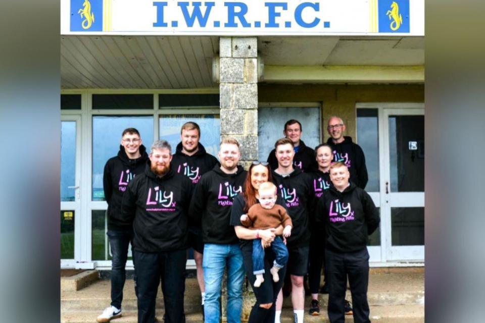 Isle of Wight County Press: Toddler, Teddy Ward, held by mum Jess, with dad Dan to her left and eight of the Three Peaks Challenge fundraisers, which includes Michael Joyce, George Huish, Sam McQueen, David Blackman, Luke Blackman, Nick Blyth, Kieran Leahy and Claire Mumford. James Bradshaw, another of the team, is not pictured as he lives on mainland.