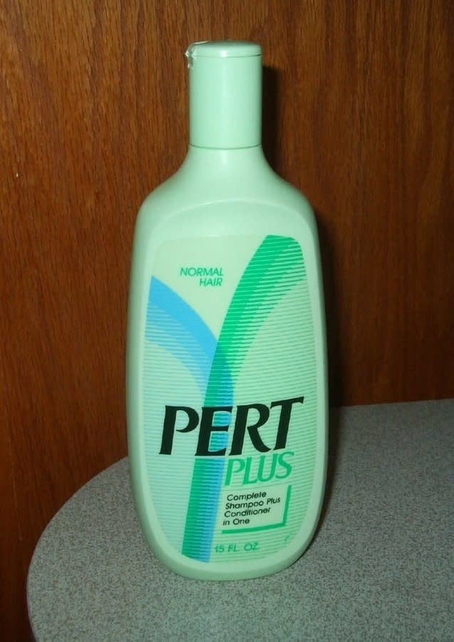 Bottle of Pert Plus shampoo for normal hair against a wooden backdrop