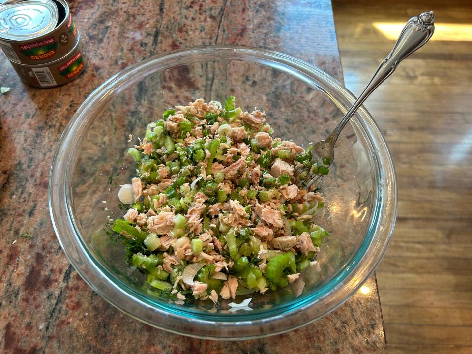 A mixture of tuna, celery, green onion, and dill in a bowl.