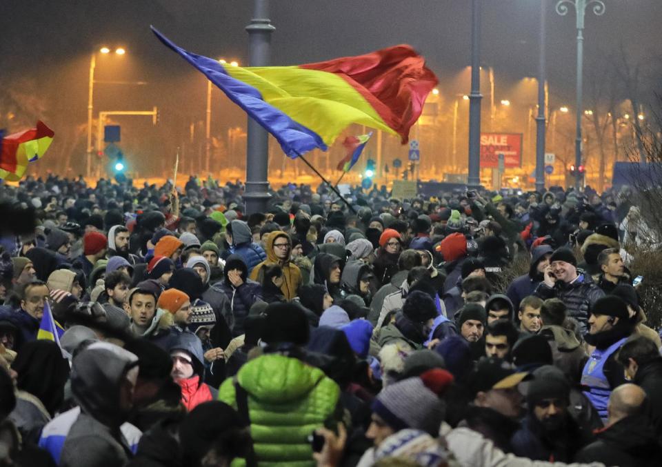 Crowds wave Romanian flags outside the government headquarters, during a protest in Bucharest, Romania, early Wednesday, Feb. 1, 2017. Romania's government adopted an emergency ordinance late Tuesday to decriminalize official misconduct, dealing a blow to a yearlong drive to curb corruption in the eastern European country. Justice Minister Florin Iordache said the measure will decriminalize cases of official misconduct in which the financial damage is valued at less than 200,000 lei ($47,800). Tens of thousands of Romanians protested against the ordinance in recent weeks, saying it would weaken anti-graft efforts. (AP Photo/Vadim Ghirda)