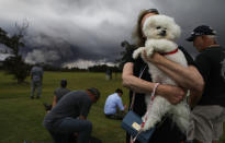 <p>A woman hold her dog Tzippy at a golf course as an ash plume rises in the distance from the Kilauea volcano on Hawaii’s Big Island on May 15, 2018 in Hawaii Volcanoes National Park, Hawaii. (Photo: Mario Tama/Getty Images) </p>