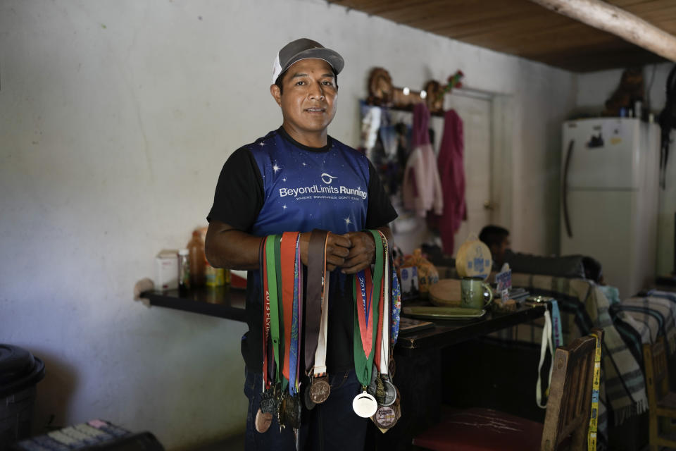 El ultramaratonista Miguel Lara posa para una fotografía con algunas de sus medallas en su casa en Porochi, una comunidad indígena en las remotas montañas Tarahumara del norte de México, el domingo 12 de mayo de 2024. (AP Foto/Eduardo Verdugo)