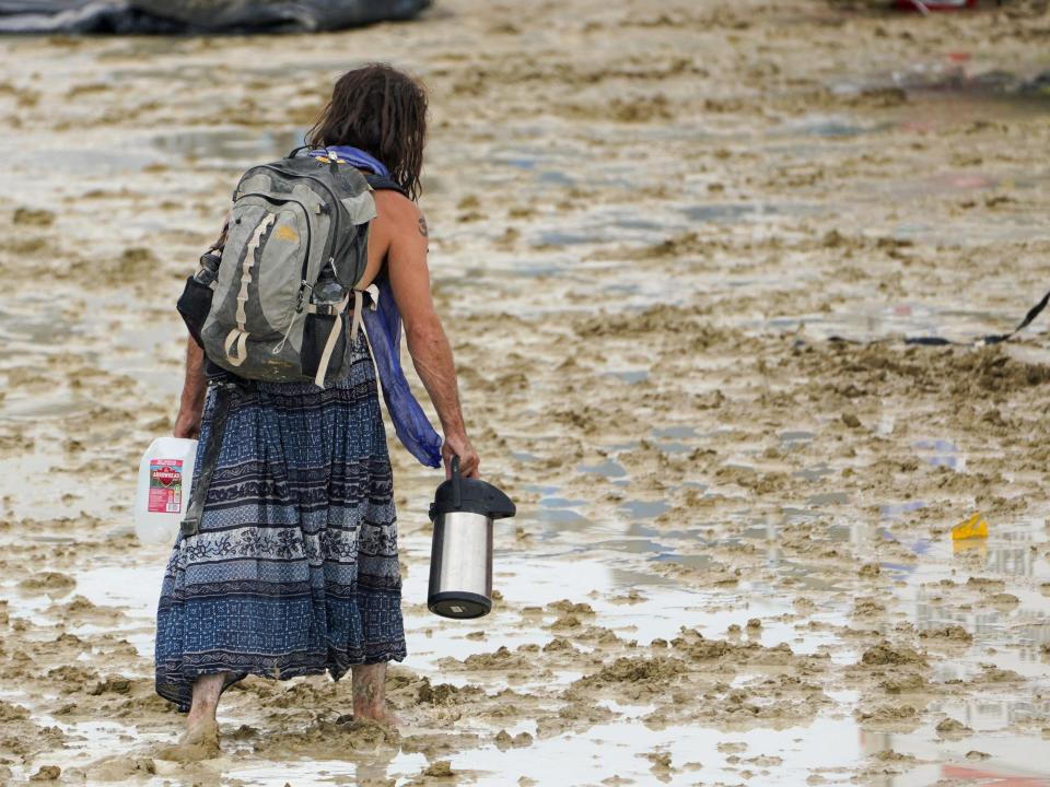 A Burning Man attendee makes their way through the mud in Black Rock, Nevada on September 2, 2023.