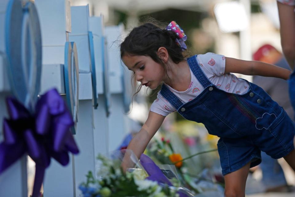 A child leaves flowers at a memorial site for the victims killed (AP)