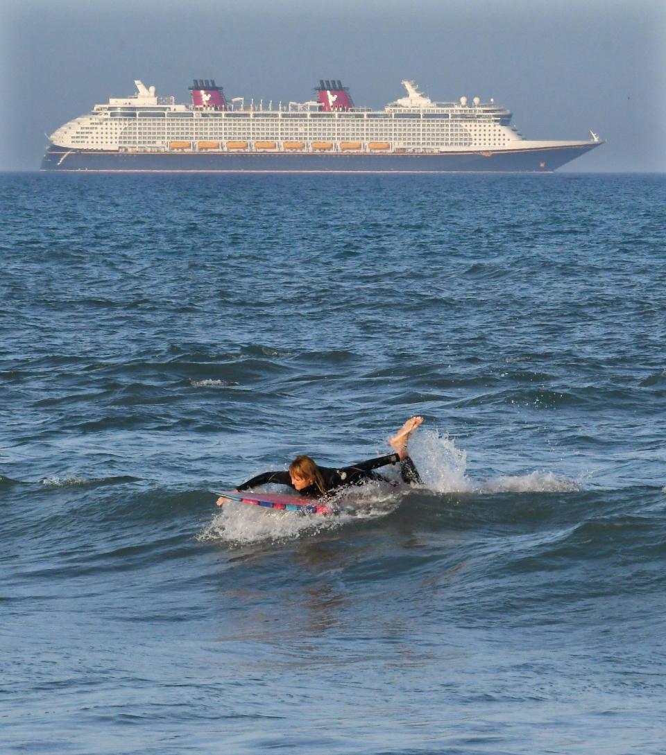 Suzanne Wagner surfs at Robert P. Murkshe Memorial Park in Cocoa Beach with a Disney Cruise ship in the background.