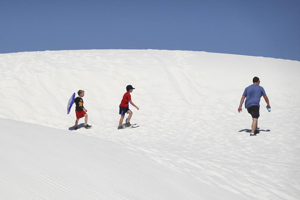 Hikers look for a dune to slide down at White Sands National Park, Monday, June 10, 2024, in White Sands, N.M. (AP Photo/Ross D. Franklin)