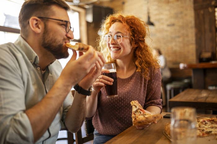 A couple sitting in a restaurant and eating pizza