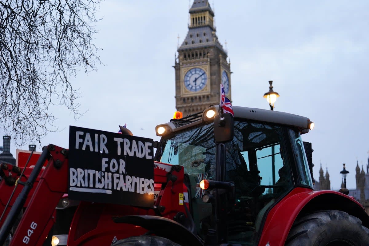 Farmers take part in a tractor 'go-slow' through Parliament Square (PA)