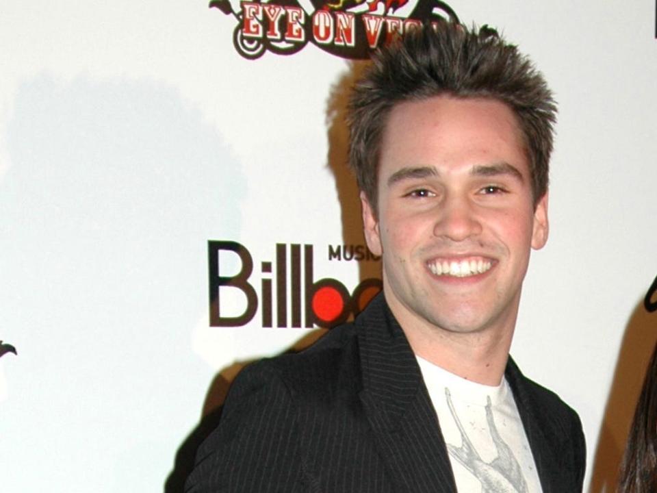 Nick smiling with spiky hair in a t-shirt and blazer.