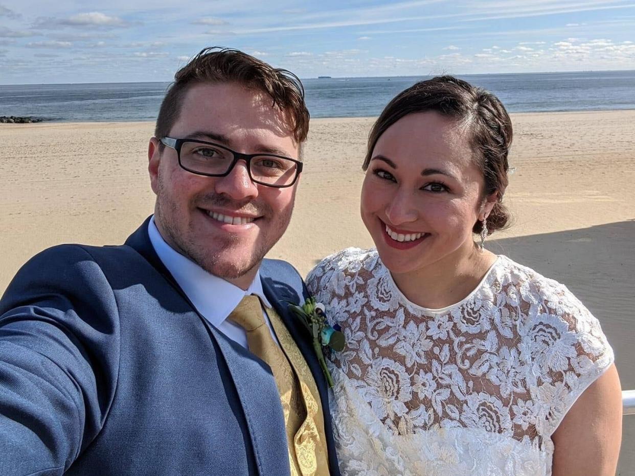 a couple takes a selfie on a beach on their wedding day