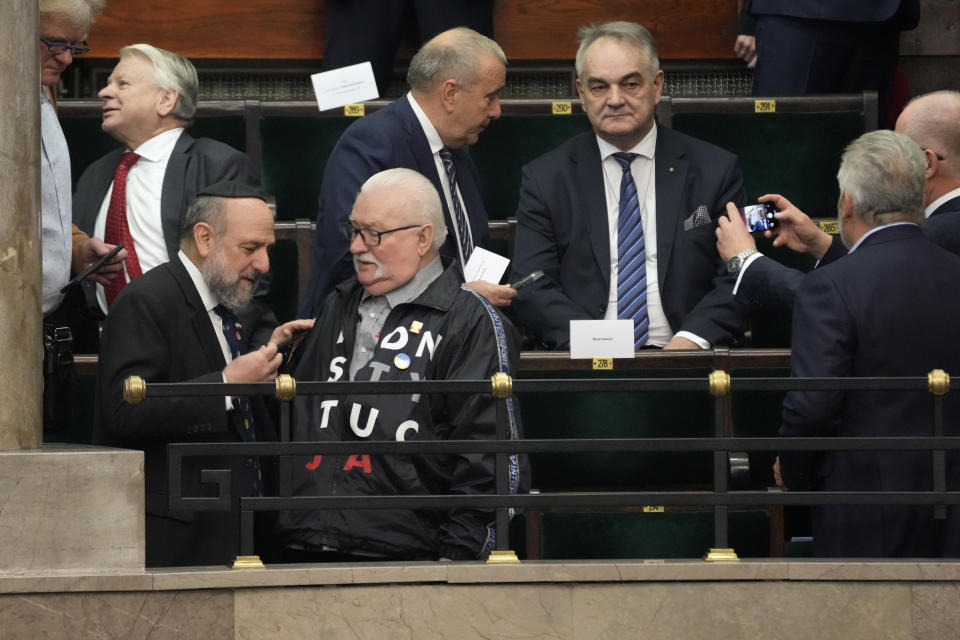 Poland's former President and Nobel Peace Prize winner, Lech Walesa, down right, arrives for a speech of newly elected Poland's Prime Minister Donald Tusk at the parliament in Warsaw, Poland, Tuesday Dec. 12, 2023. (AP Photo/Czarek Sokolowski)