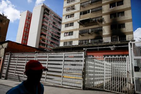 A man walks past a building where damages are seen after an explosion in Caracas, Venezuela August 5, 2018. REUTERS/Adriana Loureiro