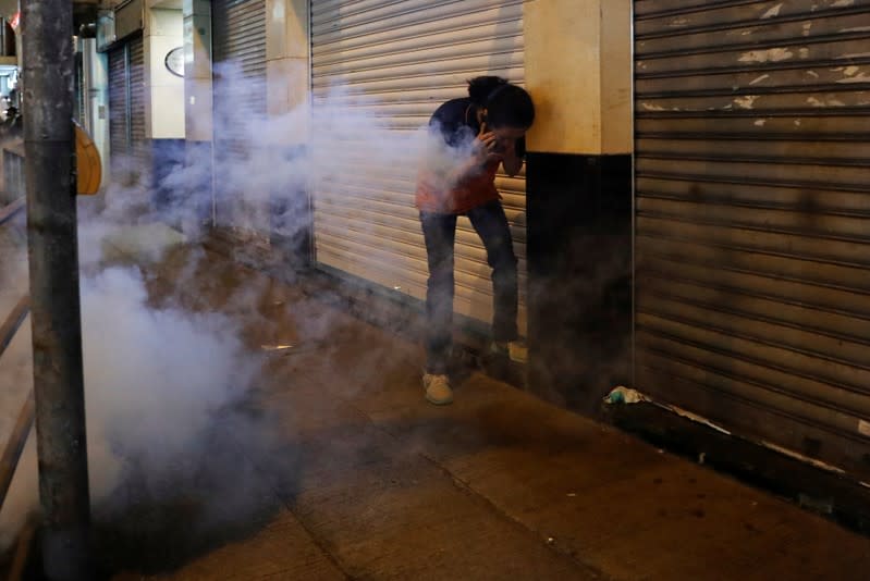 A woman reacts from tear gas during a march billed as a global "emergency call" for autonomy, in Hong Kong