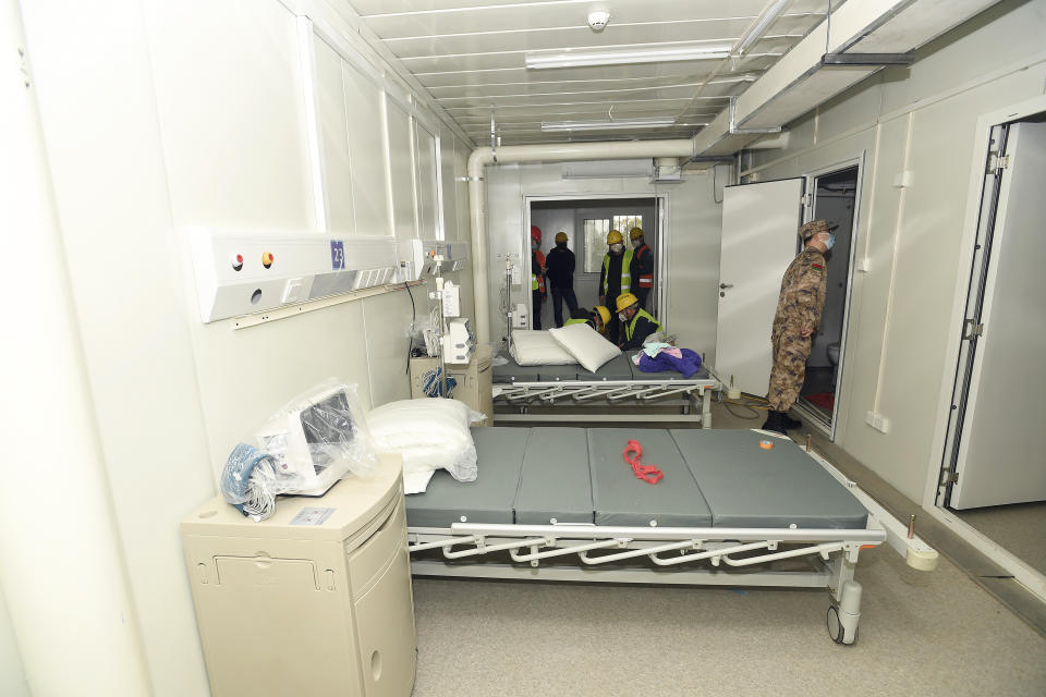 A Chinese army medic looks at a patient room at the Huoshenshan temporary field hospital in Wuhan in central China's Hubei Province, Sunday, Feb. 2, 2020. The Philippines on Sunday reported the first death from a new virus outside of China, where authorities delayed the opening of schools in the worst-hit province and tightened quarantine measures in a city that allow only one family member to venture out to buy supplies. (Chinatopix via AP)