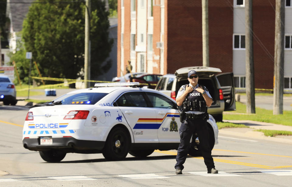 A police officer blocks the area of a shooting in Fredericton, New Brunswick, Canada on Friday, Aug. 10, 2018. Fredericton police say two officers were among four people who died in a shooting Friday in a residential area on the city's north side. One person was in custody, they said, and there was no further threat to the public. (Keith Minchin/The Canadian Press via AP)