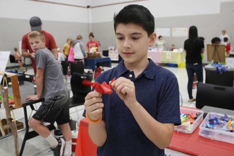 Lenexa resident Coleman Zentner, 10, shows off one of the paper cranes he was selling at his origami booth at the KidsFest Business Fair in Shawnee Sept. 9.