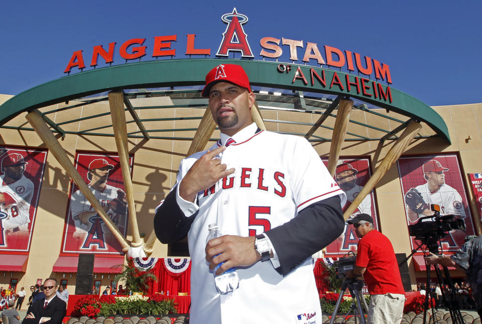 FILE - In this Dec. 10, 2011, file photo, Los Angeles Angels' Albert Pujols wears his new jersey after a news conference to introduce Pujols and C.J. Wilson (not pictured) as the newest Angels baseball players in Anaheim, Calif. Pujols has been designated for assignment by the Los Angeles Angels, abruptly ending the 41-year-old superstar slugger's decade with his second major league team. The Angels announced the move Thursday, May 6, 2021, a day after Pujols wasn't in their lineup for their fourth consecutive loss. (AP Photo/Alex Gallardo, File)