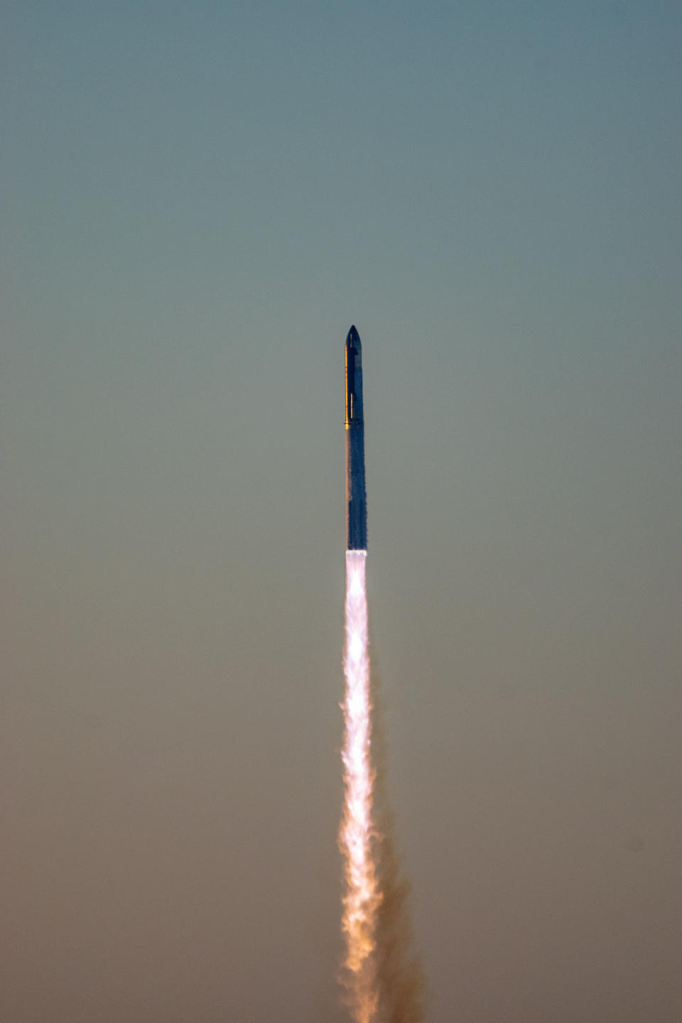 A huge rocket takes off in a pillar of fire at dawn.