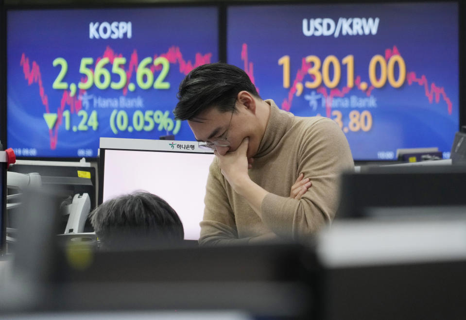 A currency trader reacts near the screens showing the Korea Composite Stock Price Index (KOSPI), left, and the foreign exchange rate between U.S. dollar and South Korean won at the foreign exchange dealing room of the KEB Hana Bank headquarters in Seoul, South Korea, Tuesday, Dec. 19, 2023. Asian shares were mixed Tuesday after a seven-week winning streak on Wall Street cooled. (AP Photo/Ahn Young-joon)