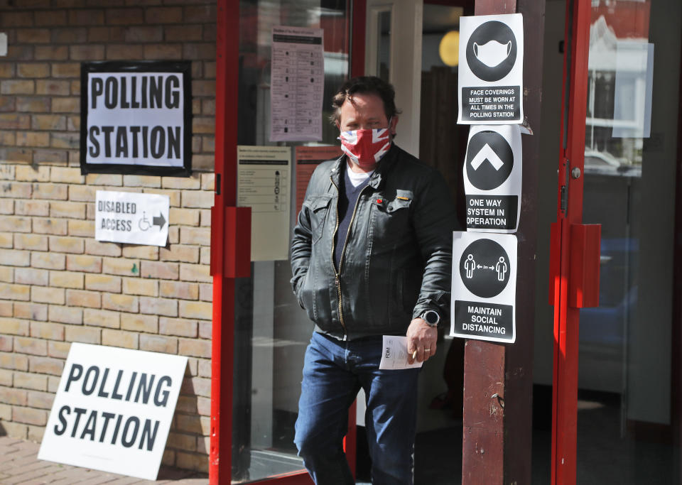 A man wearing a face mask leaves the polling station at St Albans Church after voting, in London, Thursday, May 6, 2021. Millions of people across Britain will cast a ballot on Thursday, in local elections, the biggest set of votes since the 2019 general election. A Westminster special-election is also taking place in Hartlepool, England.(AP Photo/Frank Augstein)