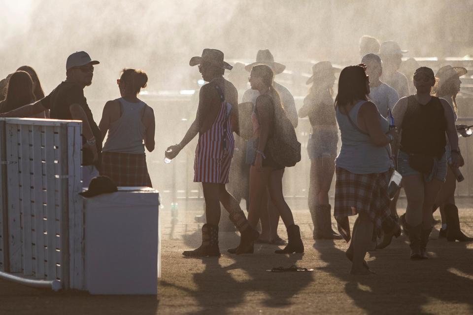Festivalgoers cool off in an area being sprayed down by festival staff at Stagecoach at the Empire Polo Club in Indio, Calif., Friday, April 28, 2023. 