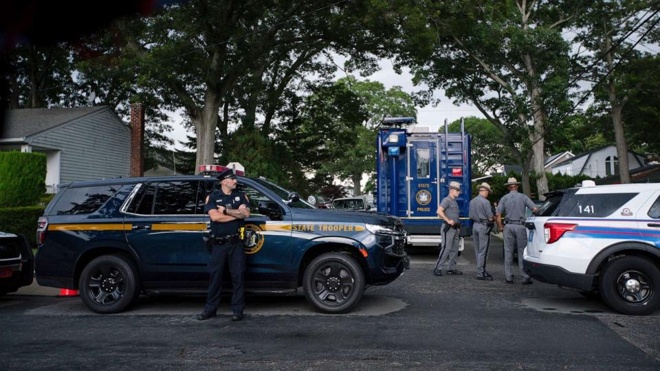 PHOTO: Police officers stand guard near the house where a suspect has been taken into custody on New York's Long Island in connection with a long-unsolved string of killings, July 14, 2023, in Massapequa, New York. (Eduardo Munoz Alvarez/AP)