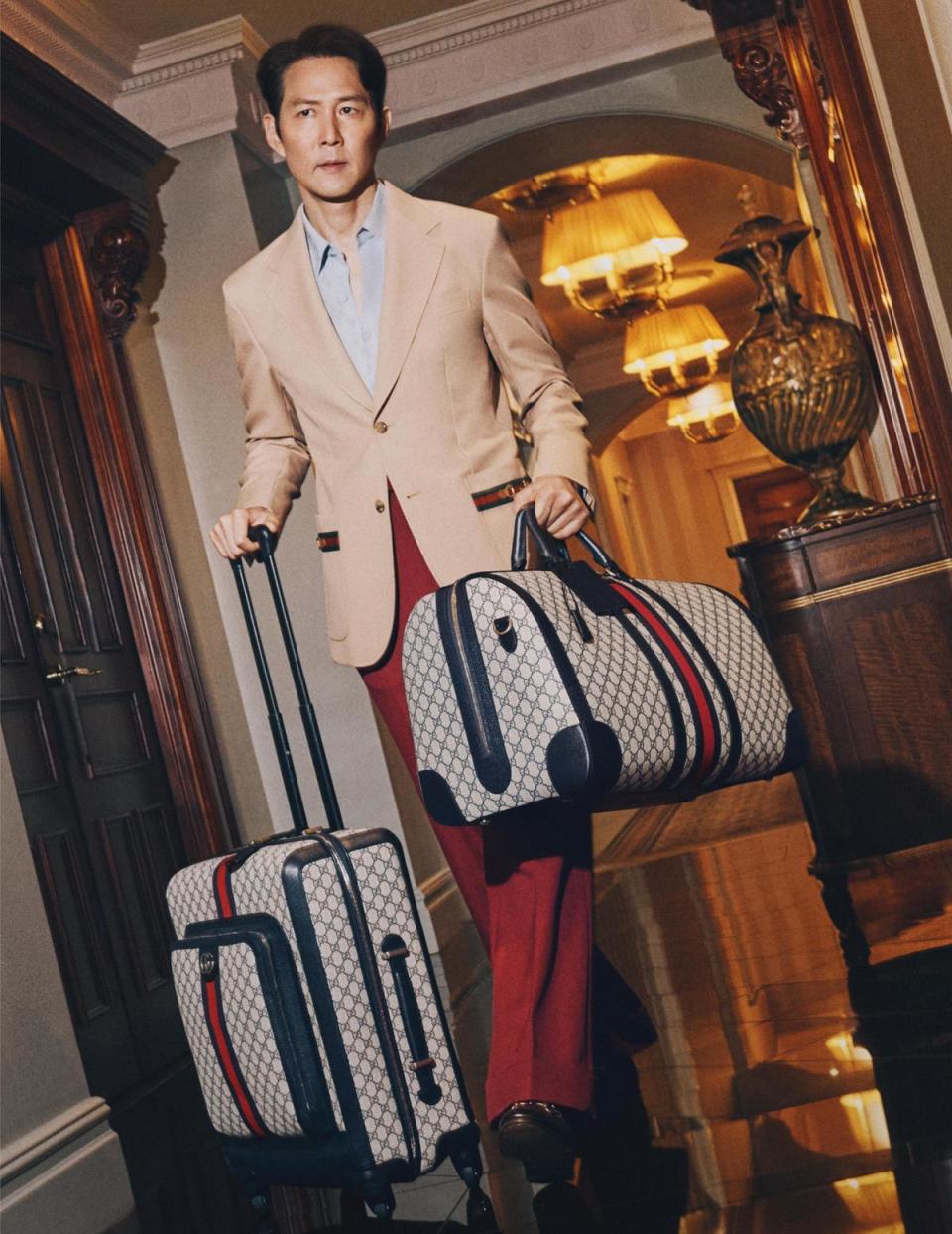 在Savoy Hotel內部廊道，李政宰拉著的Savoy系列小型登機箱與大型旅行包，是從舘藏檔案擷取的經典配色，呼應品牌的歷史源起。（古馳提供）