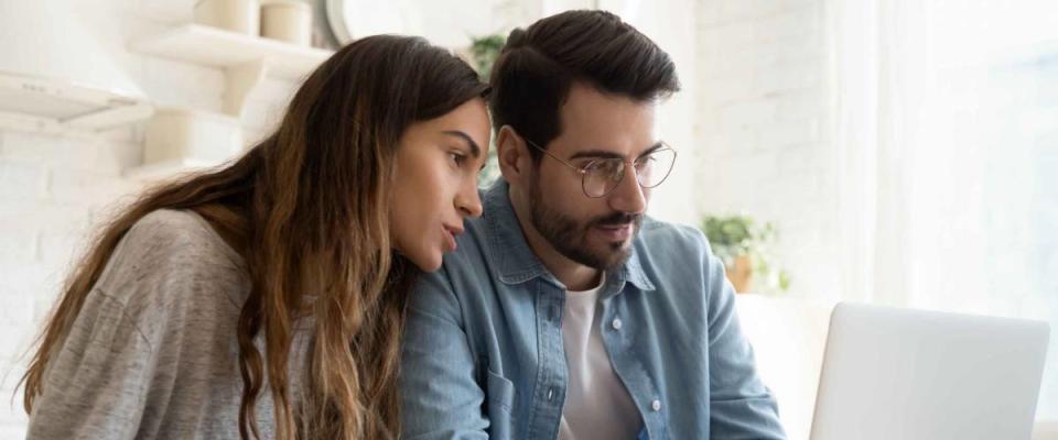 Focused young couple calculating bills, discussing planning budget together at kitchen table