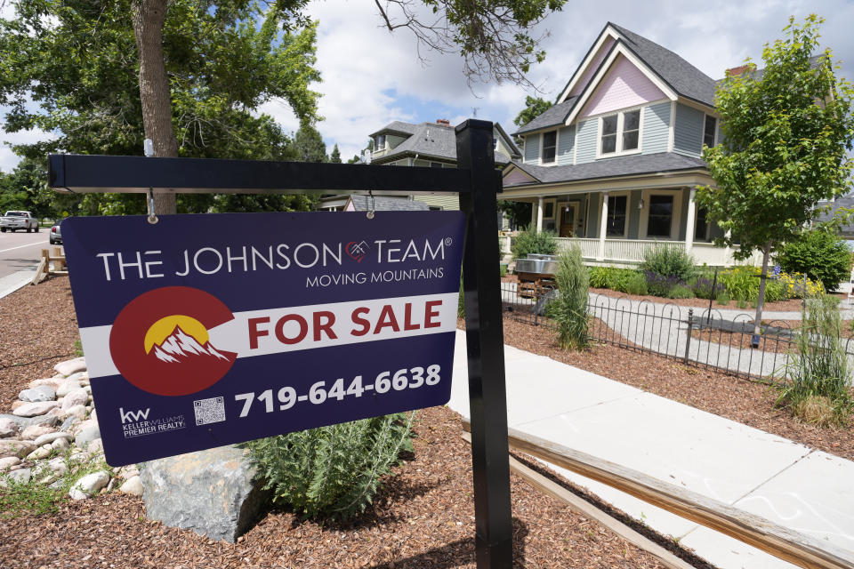 A for sale sign stands in the yard of a home in Colorado.