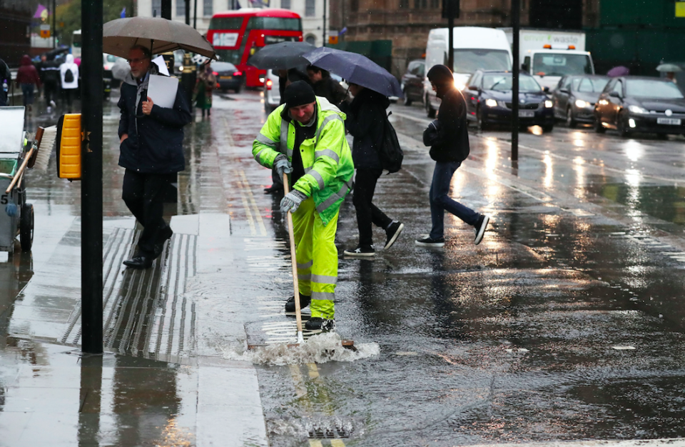 <em>A council worker clears water from a pedestrian crossing in Westminster, London as Storm Gareth sweeps across the country (PA)</em>