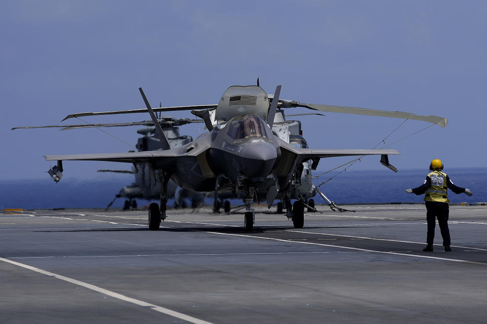 A crew member makes a signal to F-35 aircraft for take off on the U.K.'s aircraft carrier HMS Queen Elizabeth in the Mediterranean Sea on Sunday, June 20, 2021. The British Royal Navy commanders say the U.K.'s newest aircraft carrier HMS Queen Elizabeth is helping to take on the "lion's share" of operations against the Islamic State group in Iraq as Russian warplanes get an up-close look at the cutting-edge F-35 jet in a "cat-and-mouse" game with British and U.S. pilots. (AP Photo/Petros Karadjias)