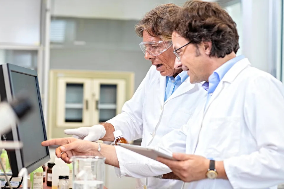 Two scientists look at a computer screen in a lab.