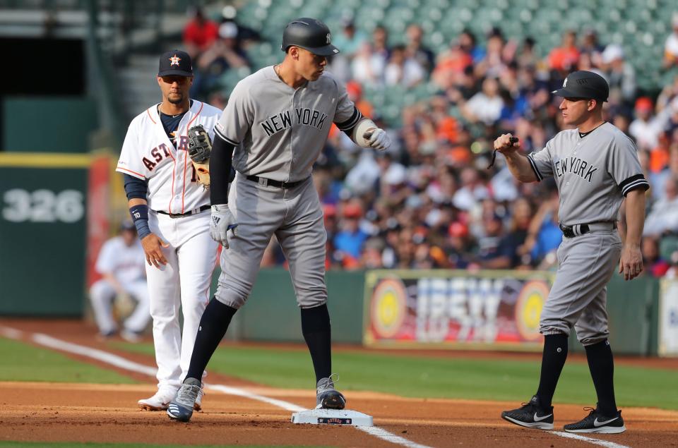 Former New York Yankees first base coach Reggie Willits (right) fist bumps with Aaron Judge (center) during a game against the Houston Astros. Willits left the Yankees to join the OU baseball coaching staff.