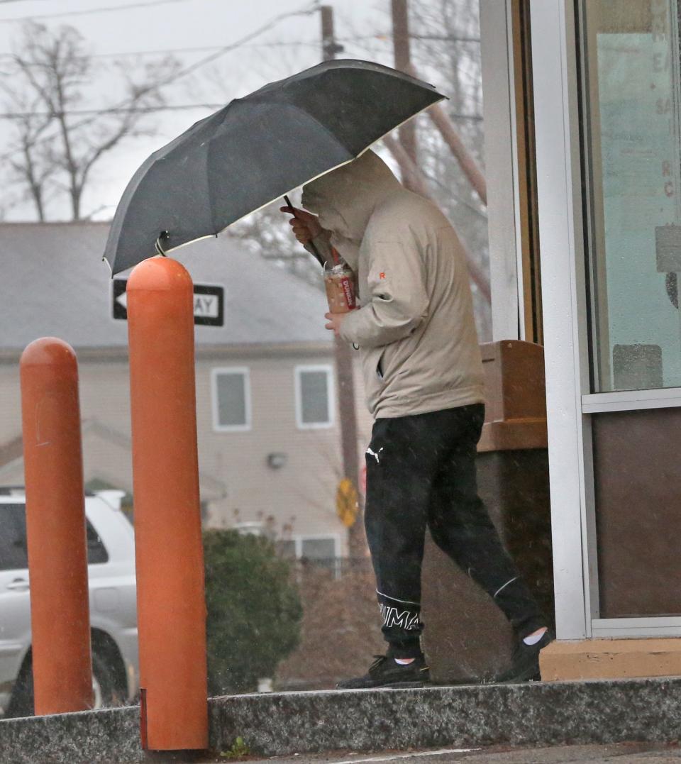 A person exits Dunkin Donuts on Centeral Avenue holding an umbrella steady with wind and rain coming at the pedestrian Dec. 18, 2023.